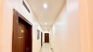 Un couloir bordé de portes en bois, numérotées 201 et 202, qui donnent accès à des pièces.