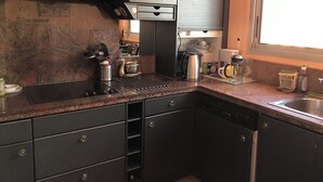 Cucina con orologio, elettrodomestici in acciaio inossidabile e una finestra.