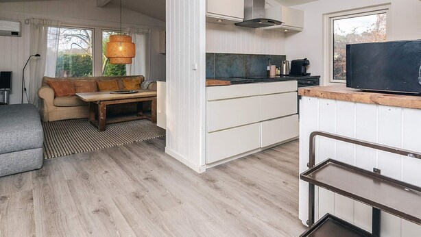 A modern kitchen with white cabinetry, a stainless steel range hood, and a black countertop. - 4 Star Holiday Home in Hornbaek (Hornbaek)