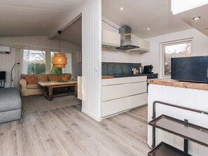 A modern kitchen with white cabinetry, a built-in stove, and a large window. - 4 Star Holiday Home in Hornbaek (Hornbaek)