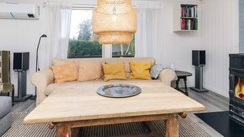 Una sala de estar con un sofá, una mesa de centro, una chimenea y una estantería.