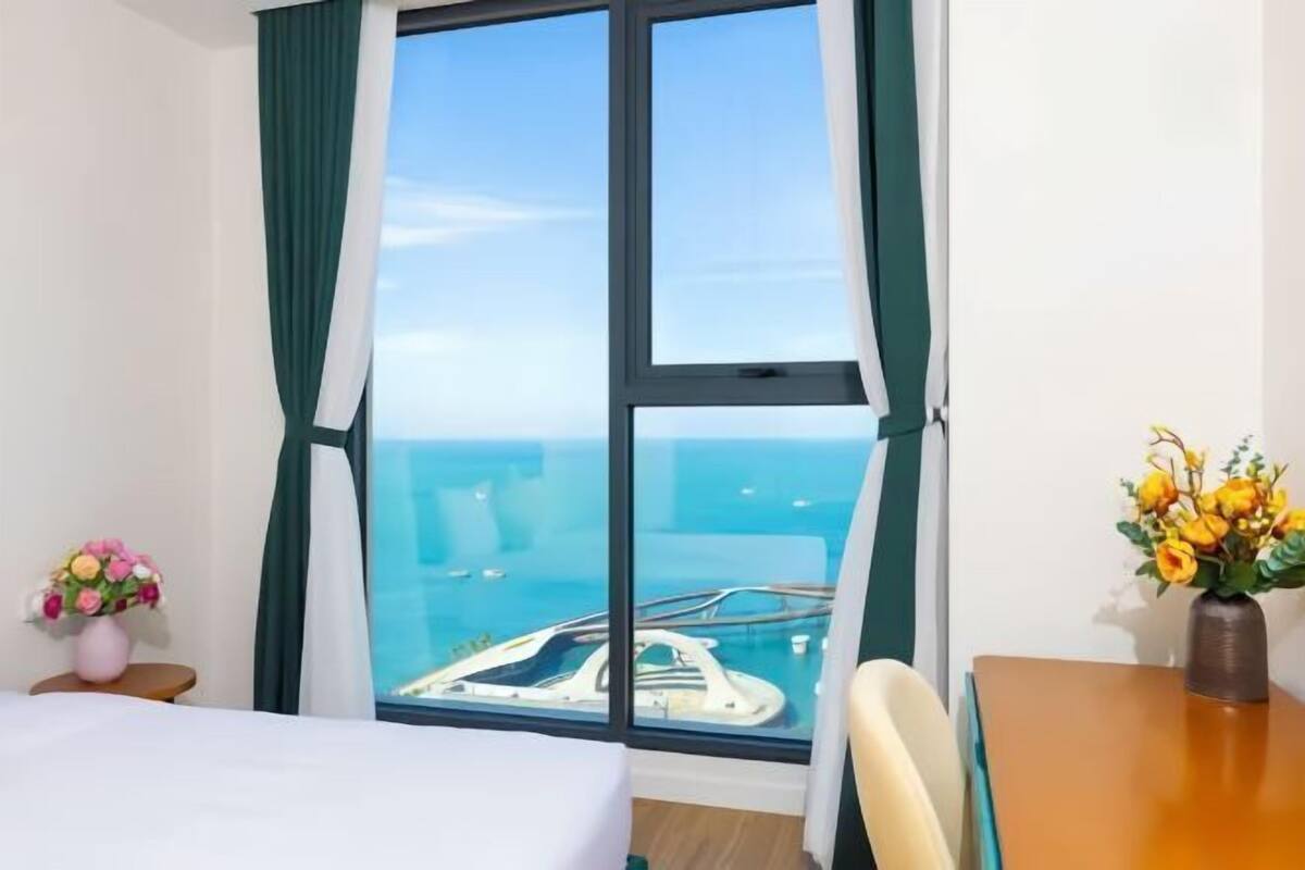 Une chambre d’hôtel avec une grande fenêtre, un lit, une table et une chaise.