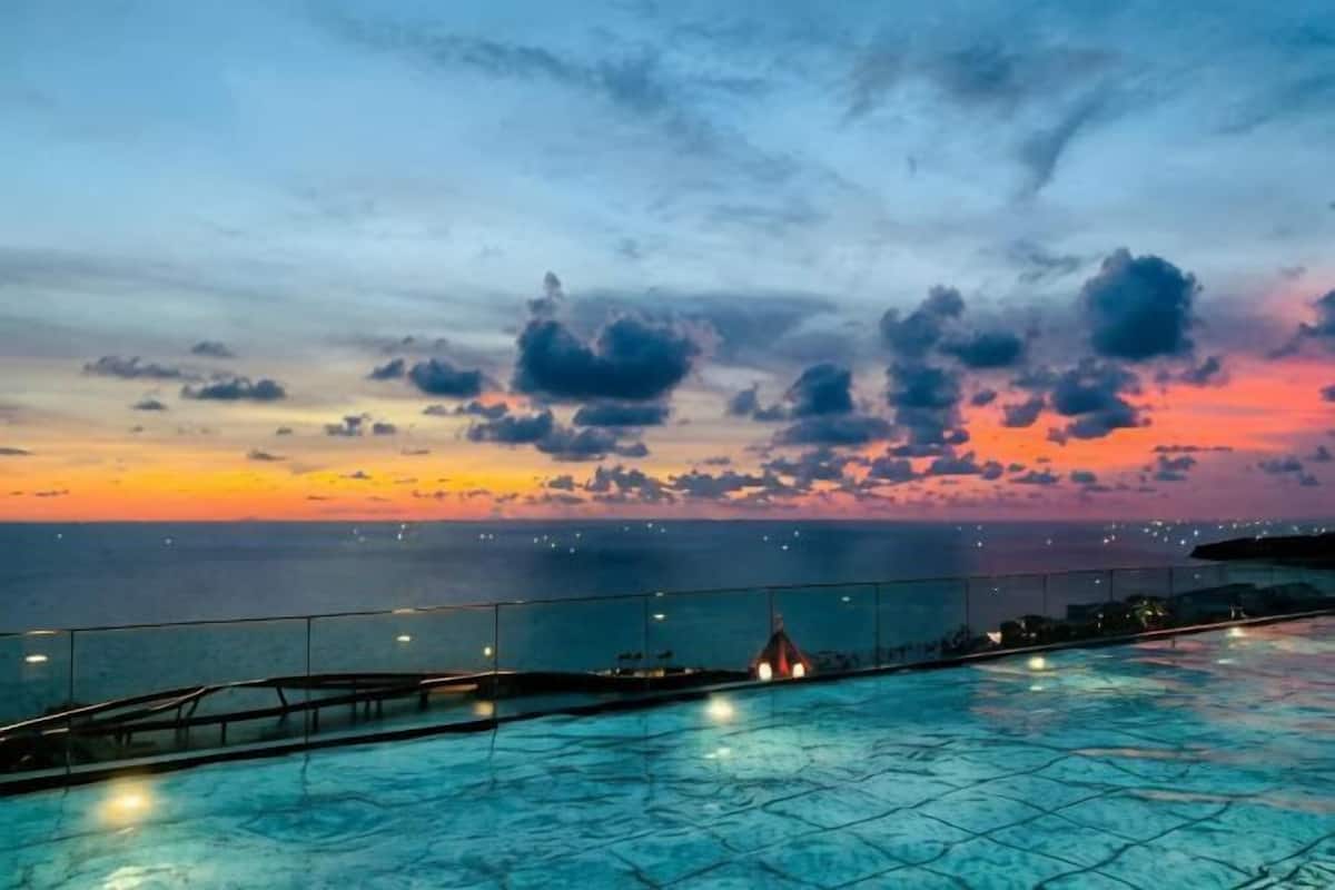 Une piscine avec vue sur l’océan au coucher du soleil.