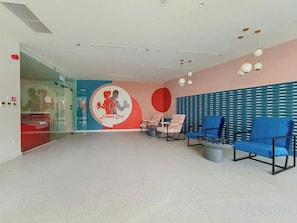 A spacious lobby with a reception desk, seating area, and a wall with a logo.