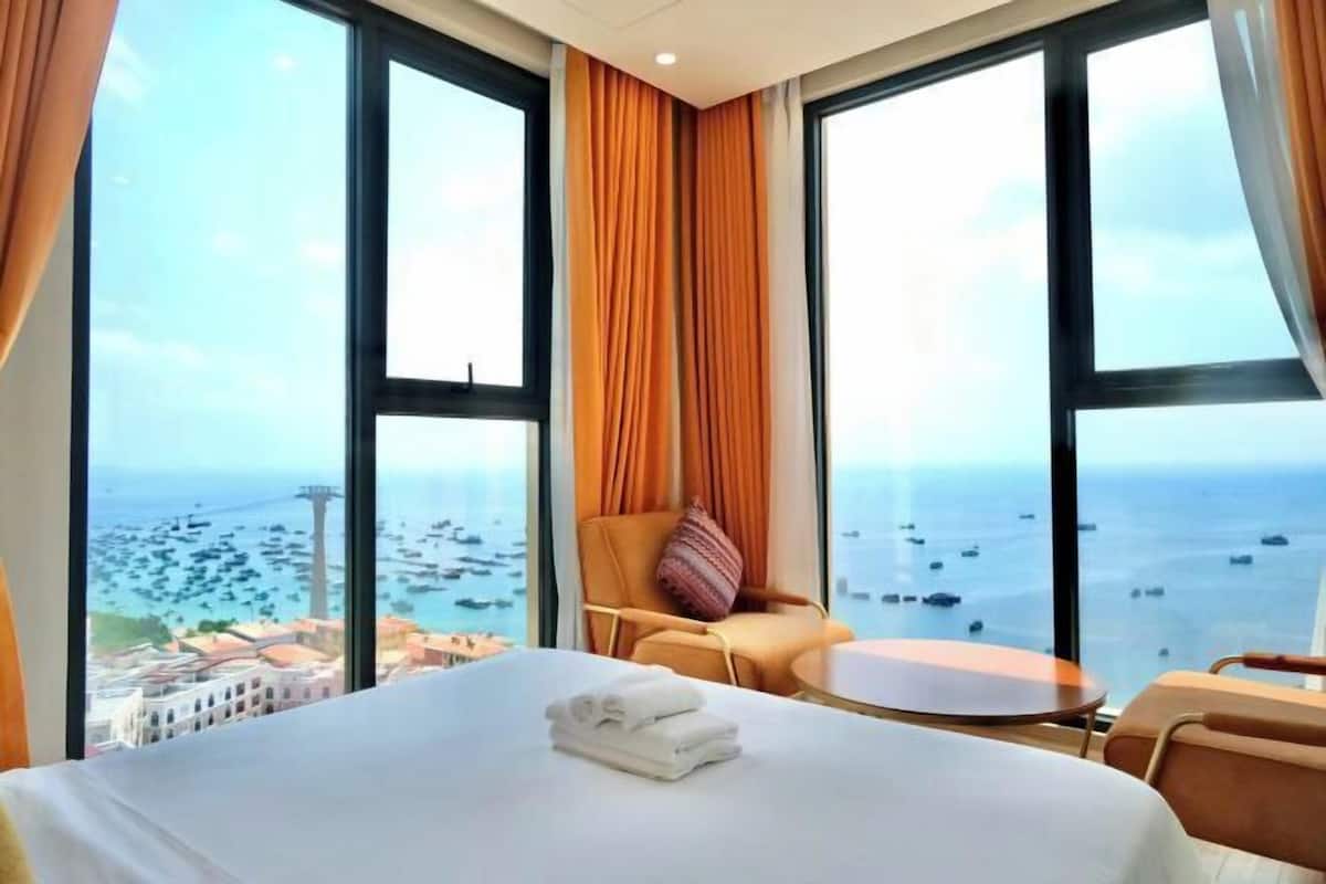 Une chambre d’hôtel avec un grand lit, une table ronde et une vue sur la mer et les bateaux.