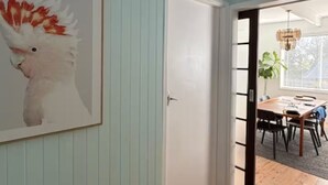 A room with light blue walls, a white door, and a wooden floor. - Caves Beach, Sea Breeze - 5 min walk to the patrolled beach and caves (Caves Beach)