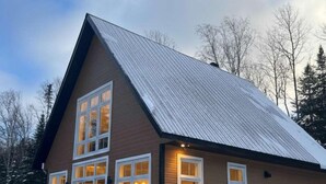 A two-story building with a sloped roof, large windows, and a snow-covered ground.