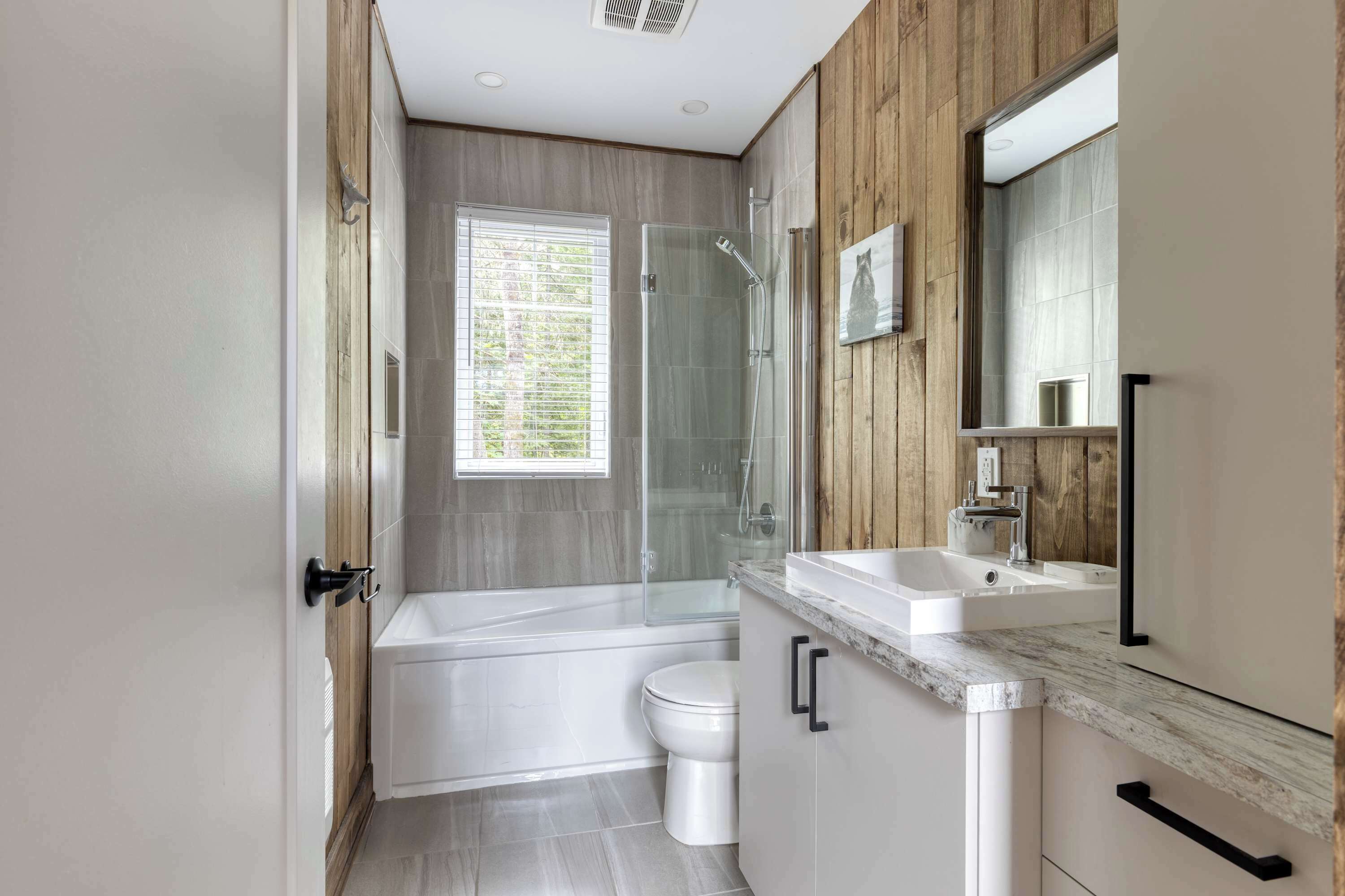 A modern bathroom with a bathtub, toilet, and shower.