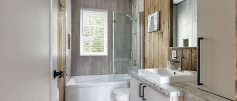 A modern bathroom with a bathtub, toilet, and shower.