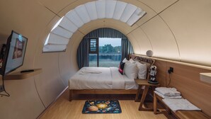 A cozy, arched bedroom with a bed, bedside table, and a TV. - Astrophile (Vada)