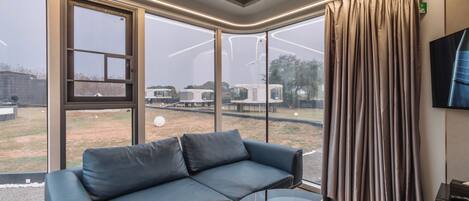 Uma sala de estar moderna com sofá de couro, mesa de centro de vidro e grandes janelas com vista para as comodidades externas.