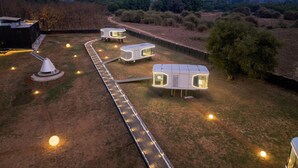 A campsite with several modern, white, modular cabins connected by a paved walkway. - Astrophile (Vada)