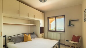 A bedroom with a bed, a window with a view, a radiator, and a chair.