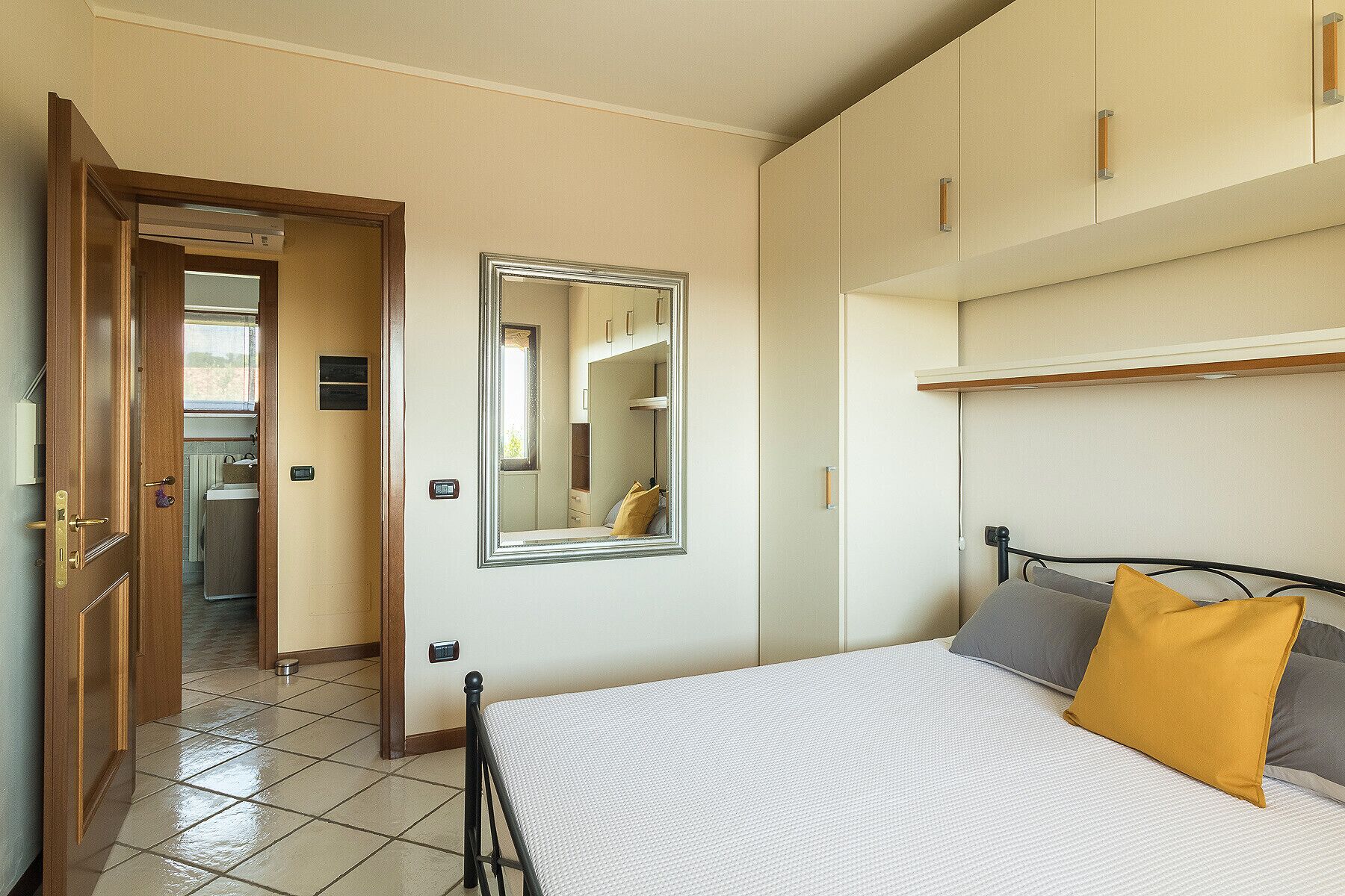 A bedroom with a bed, a mirror, and a wardrobe.