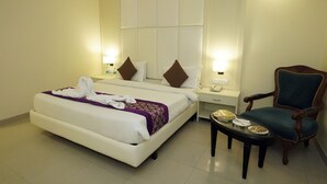 A hotel room with a bed, bedside tables, a chair, and a small table with food items. - Hotel Om Tower & Revolving Restaurant  (Jaipur)