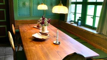 Un coin repas avec une table en bois, des chaises, des lampes suspendues et une fenêtre avec des rideaux.