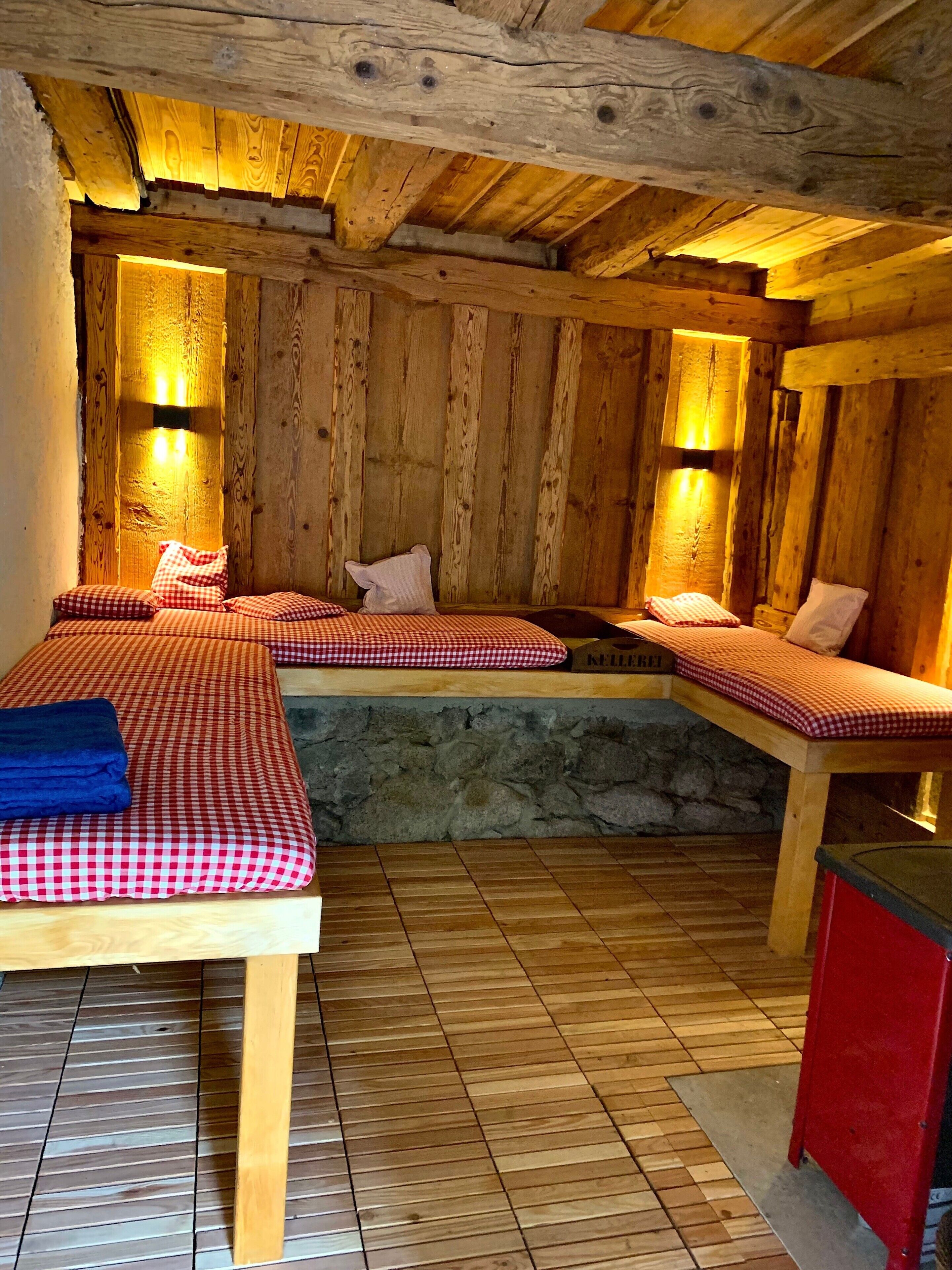 Une pièce rustique en bois, avec deux lits, un mur en pierre et des poutres apparentes.