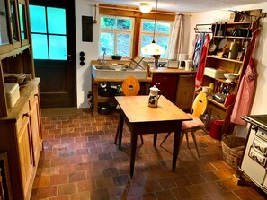 A kitchen with a wooden table, a stove, and a window with curtains.