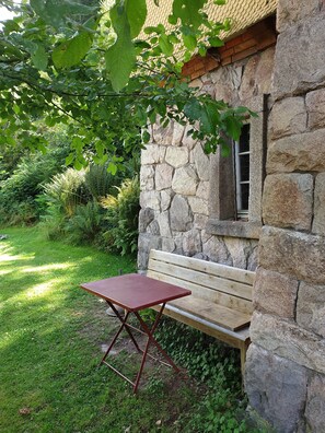 A stone building with a wooden bench and a small table.