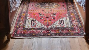 Una habitación con dos camas, un aparador de madera, una alfombra y un ventanal con cortinas.