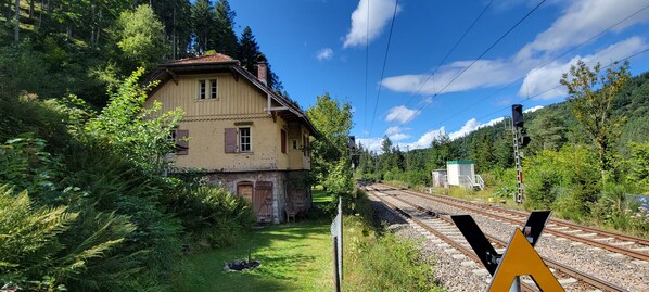 Una casa junto a las vías del tren, rodeada de vegetación y árboles.