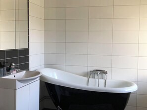 A modern bathroom with a freestanding bathtub, a sink, and a mirror. - Villa Tina (Hammarstrand)
