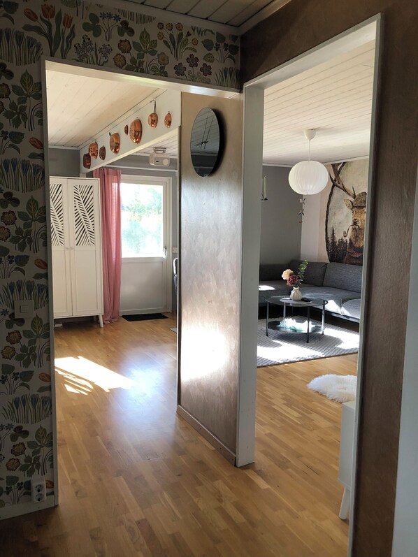 A modern living room with a sofa, coffee table, and decorative items. There is a wooden floor and a door leading to another room. - Villa Tina (Hammarstrand)