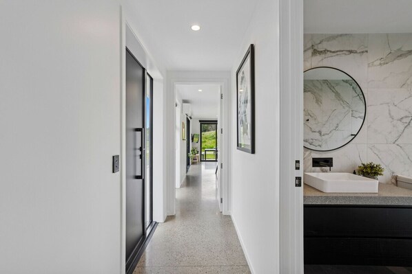 A modern hallway with a marble wall and a large mirror. - Luxury Coronet Residence (Queenstown)