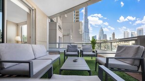 A modern outdoor seating area with a view of a city skyline. -  Durrani Homes - Azure 2BR with Burj Khalifa and Fountain View (Dubai)