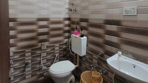 A small bathroom with a toilet, sink, and shower. - HOTEL ARADHANA (Veraval)