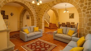 A spacious living area with two sofas, a fireplace, and a staircase leading to an upper floor.