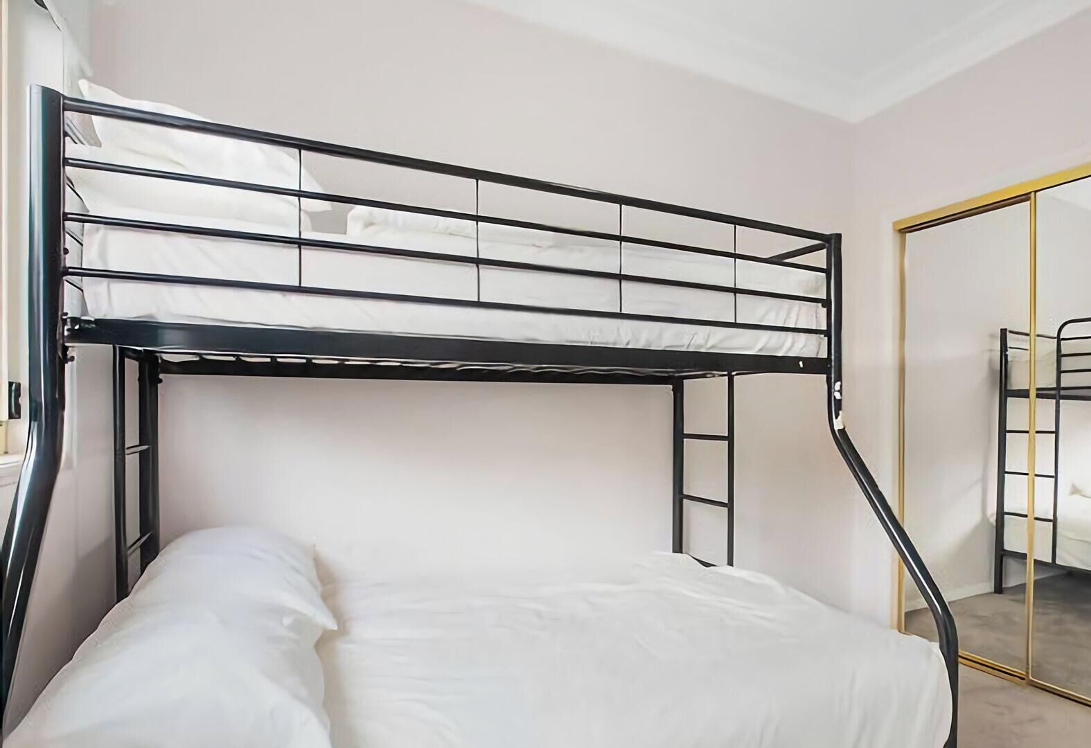 A bunk bed with a metal frame and white bedding.