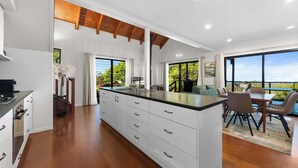 A modern kitchen with a large island, white cabinetry, and a dining area with a view. - Havenwood Chalet 2 Bedrooms (Ravensbourne)