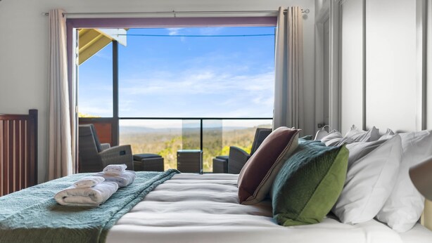 A hotel room with a bed, a view of the desert through a large window, and a balcony with chairs. - Havenwood Chalet 2 Bedrooms (Ravensbourne)