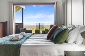 A hotel room with a bed, a view of the desert through a large window, and a balcony with chairs. - Havenwood Chalet 2 Bedrooms (Ravensbourne)