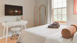 A bedroom with a bed, a desk, a chair, a TV, a window with curtains, and a mirror. - Cozy 1BD In The Heart Of Rittenhouse Square (Philadelphia)