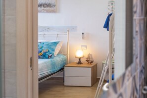 A bedroom with a bed, bedside table, lamp, and a wall-mounted phone. - Azure Bay Luxury Villa (Torre Squillace)