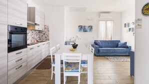 Una cucina moderna con tavolo da pranzo, sedie e un divano blu in un ambiente luminoso.