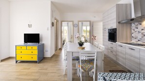 Una cucina moderna con zona pranzo, una TV su un mobile e vista sul tinello.