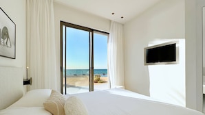 A hotel room with a large bed, a TV, and a sliding glass door leading to a balcony with a view of the sea. - Solemar Sicilia - Villa Gloria (Ficarazzi)