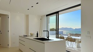 A modern kitchen with a large island, a built-in sink, and a view of the sea. - Solemar Sicilia - Villa Gloria (Ficarazzi)