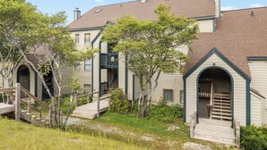A two-story building with a central staircase, a covered porch, and a small garden area.