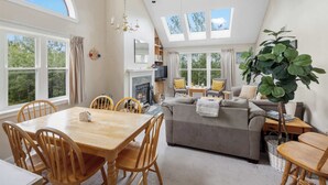 A spacious living area with a fireplace, a dining table with chairs, a sofa, and a large plant.