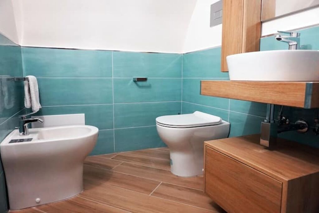 A bathroom with a bidet, toilet, and a sink with a mirror above it.
