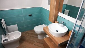 Une salle de bain équipée d’un bidet, de toilettes et d’un lavabo, avec des carreaux de couleur turquoise et des éléments décoratifs en bois.