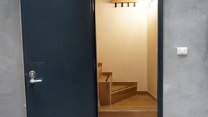 Une porte bleu foncé avec une poignée argentée, qui donne sur un escalier en bois surmonté d’un banc en bois.