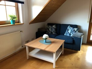 Une pièce avec une table en bois, un canapé bleu et une fenêtre avec une plante.