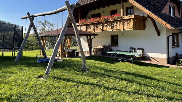 Une maison avec un balcon, une balançoire et un espace patio.