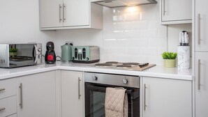 Eine moderne Küche mit weißen Schränken, einer Edelstahl-Dunstabzugshaube, einer Mikrowelle, einem Toaster und einem Wasserkocher.
