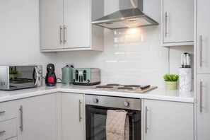 Eine moderne Küche mit weißen Schränken, einer Edelstahl-Dunstabzugshaube, einer Mikrowelle, einem Toaster und einem Wasserkocher.